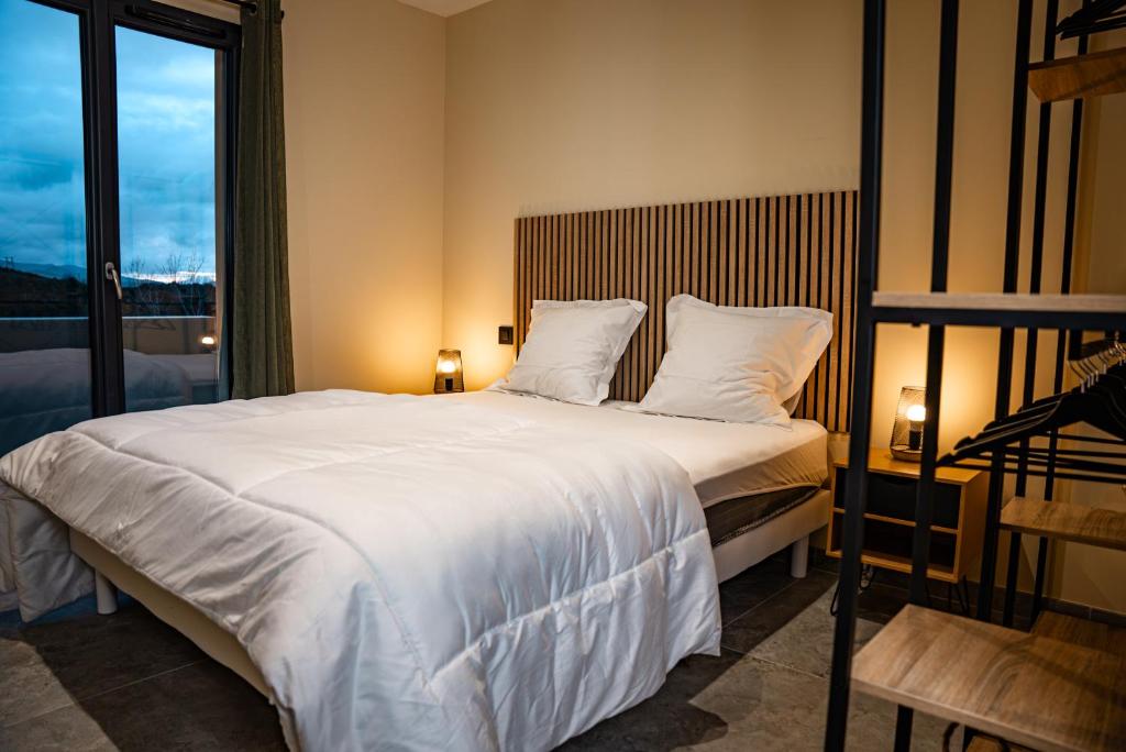 - une chambre avec un grand lit blanc et une fenêtre dans l'établissement A CASA DI LAURENA piscine chauffée proche St Florent, à Vallecalle