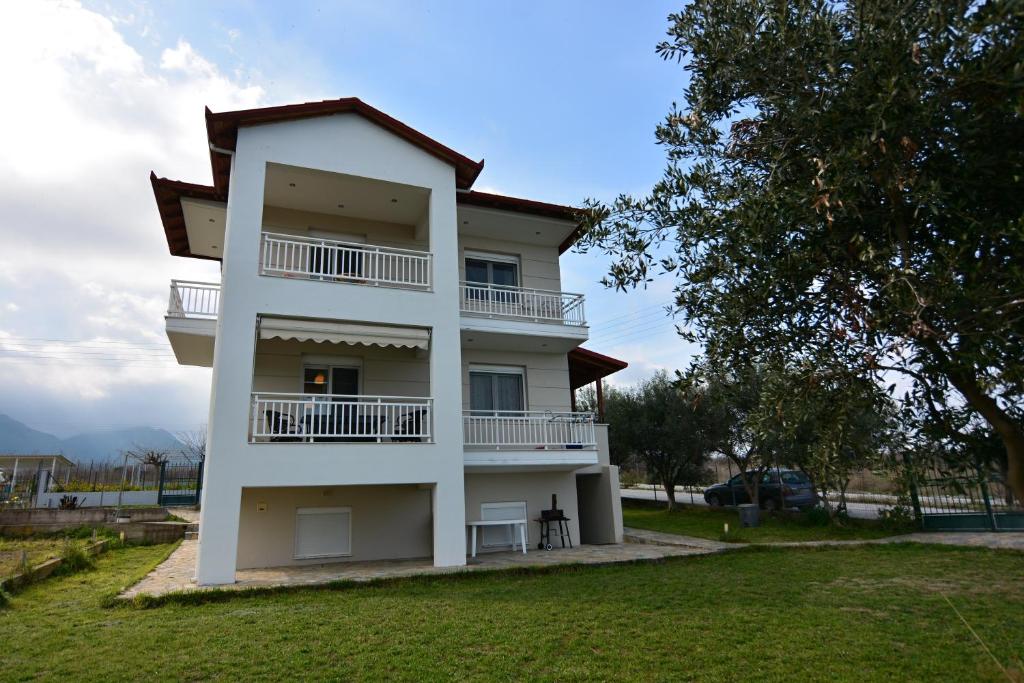 - un bâtiment blanc avec un balcon et un arbre dans l'établissement Oikia Olympus, à Leptokaryá