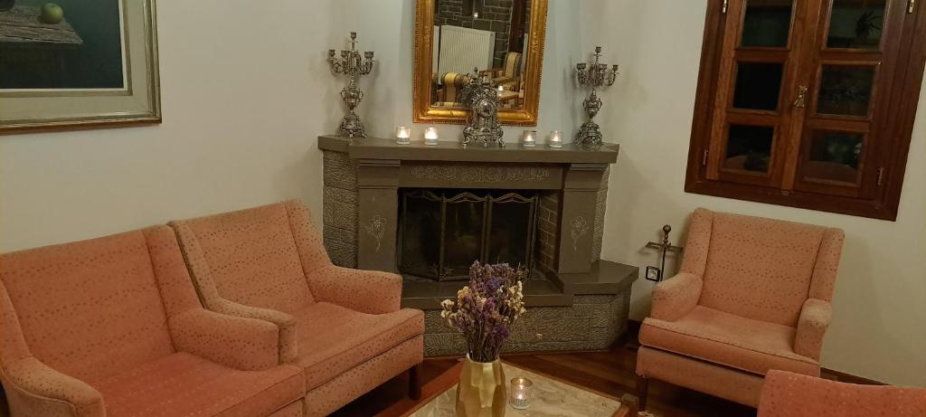 a living room with two chairs and a fireplace at Archontiko Tzoumerkon in Ágnanta