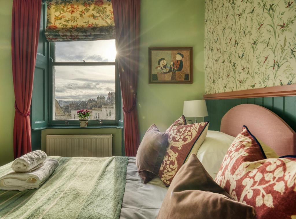 Bett in einem Zimmer mit Fenster und einem Bett mit Kissen in der Unterkunft Hill House in Bath