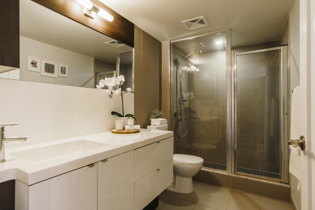 a white bathroom with a shower and a toilet at Jarvis Suites in Toronto