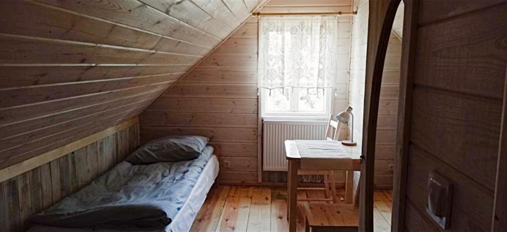 Habitación con cama y escritorio en una habitación de madera. en Gościniec Pod Dębami I, 