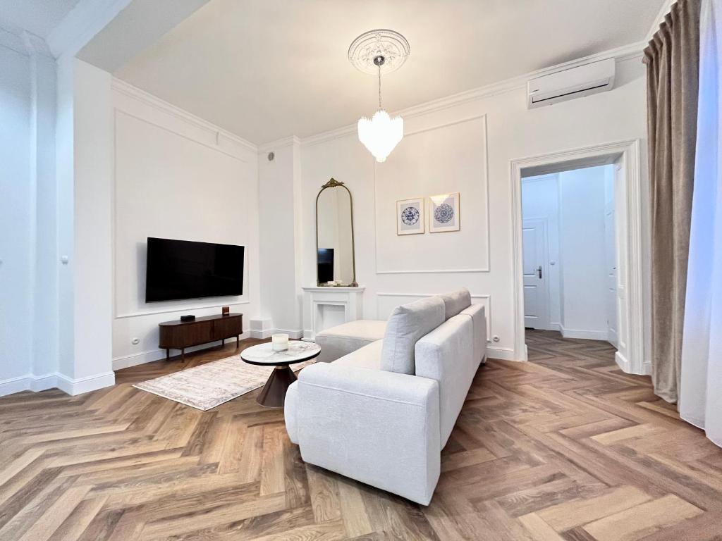 Apartamenty Lubin - Noclegi Lubin في لوبين: غرفة معيشة مع أريكة بيضاء وتلفزيون