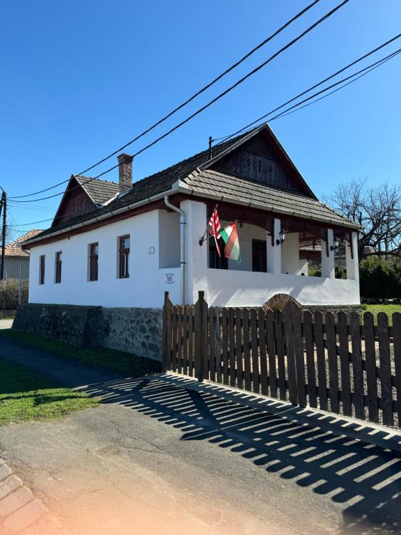 una casa blanca con una valla de madera delante de ella en Karaván guest house, en Hollókő
