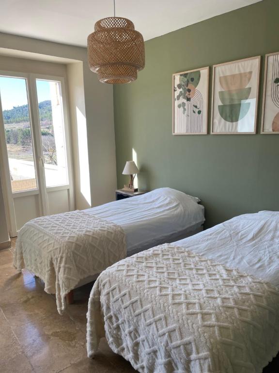 a bedroom with two beds and a window at Domaine de Prefaissal in Mézel