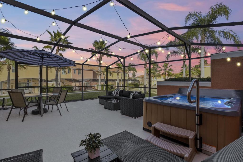 a patio with a hot tub and a table and chairs at Townhouse Near Disney Sleeps 10 Guests & Dog-Friendly! in Kissimmee
