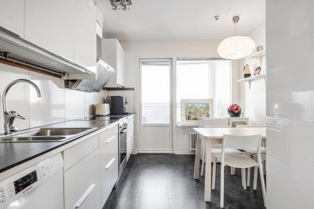 une cuisine avec des appareils électroménagers blancs et une table avec des chaises dans l'établissement Quiet City Style Apartment, à Täby