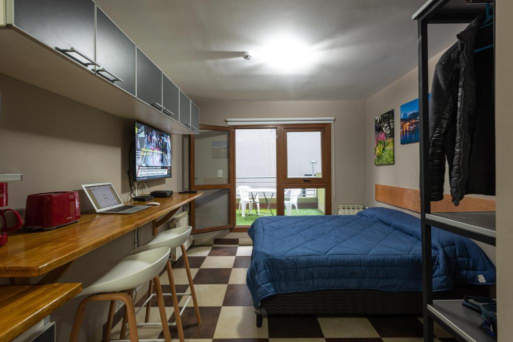 a bedroom with a bed and a desk with a laptop at Gente del Sur - Godoy in Ushuaia