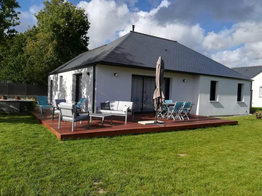 une maison avec une terrasse dotée de chaises et d'un parasol dans l'établissement Location proche plage de Penvins, Sarzeau, à Sarzeau