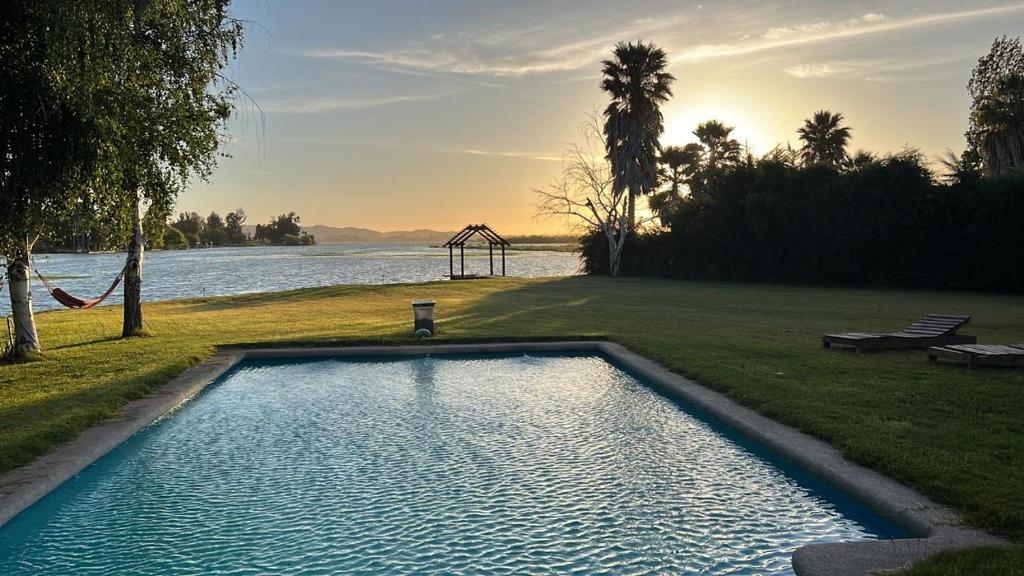 a swimming pool sitting next to a body of water at Preciosa Casa con Piscina y muelle en orilla Lago Rapel in Las Cabras