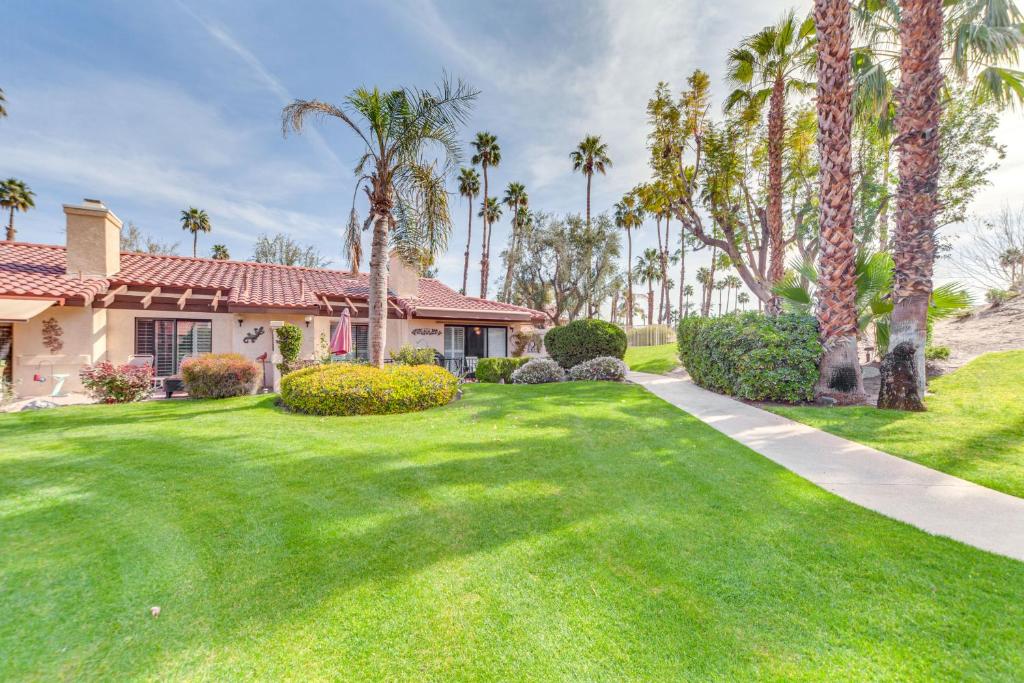 a house with palm trees and a green yard at Palm Desert Home with Pool Access - Near Golfing! in Palm Desert