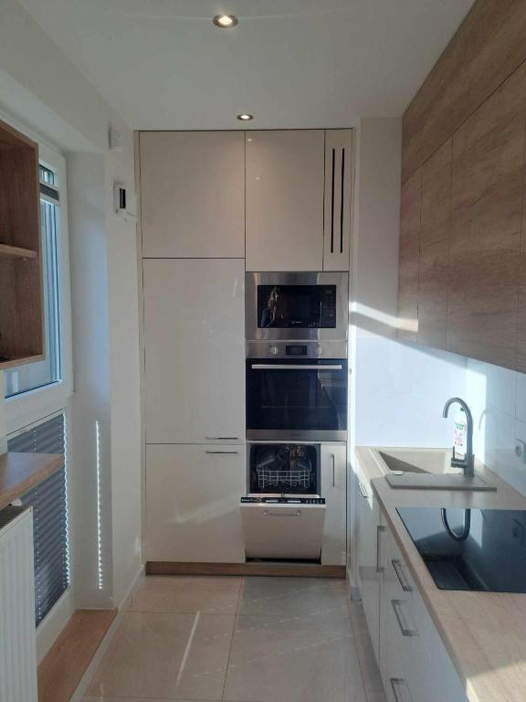 a kitchen with white cabinets and an oven and a sink at Słońce Bemowa in Warsaw