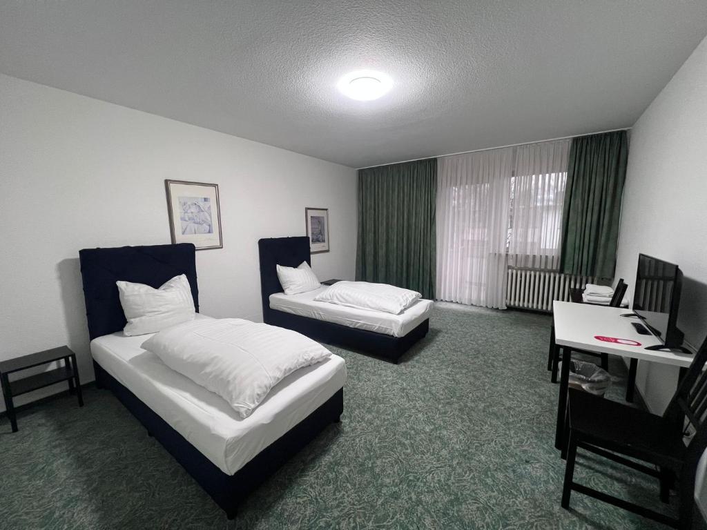 レバークーゼンにあるHaven - Hotel Am Stadionのベッド2台とデスクが備わるホテルルームです。