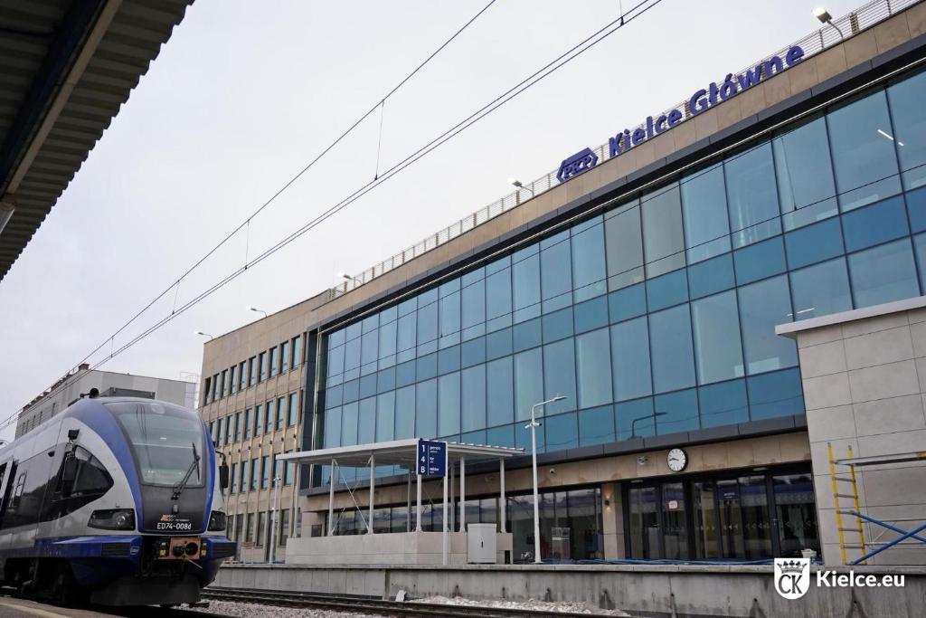 a train is on the tracks next to a building at Apartamenty Dworcowe Stacja Centrum Kielce in Kielce