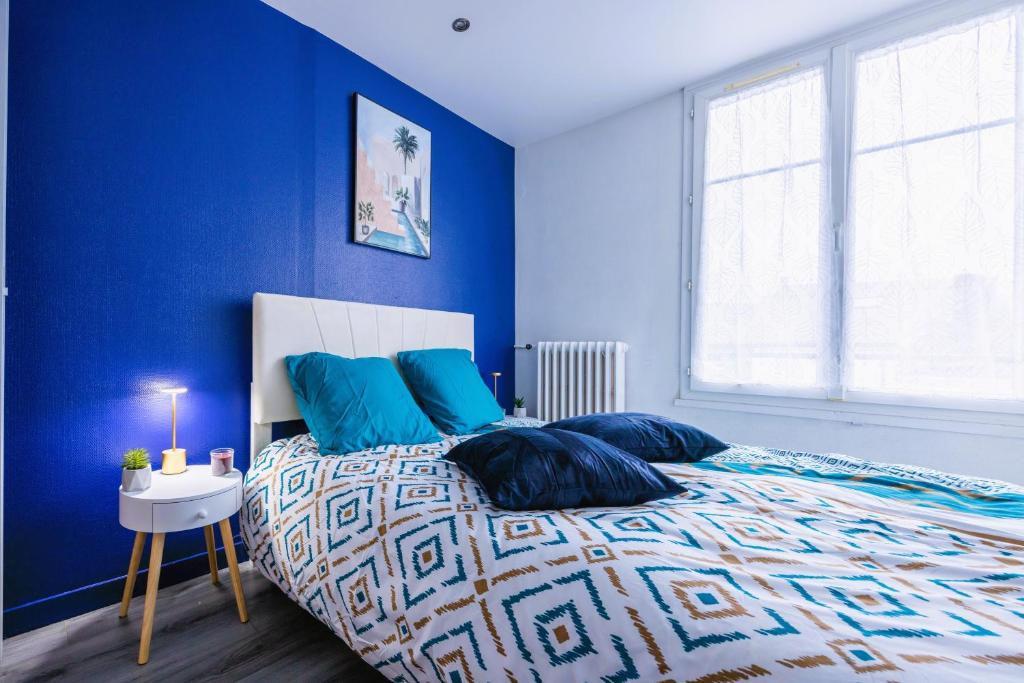 une chambre avec des murs bleus et un lit avec des oreillers bleus dans l'établissement Appartement de standing - coeur de Rezé / 10min de Nantes, à Rezé