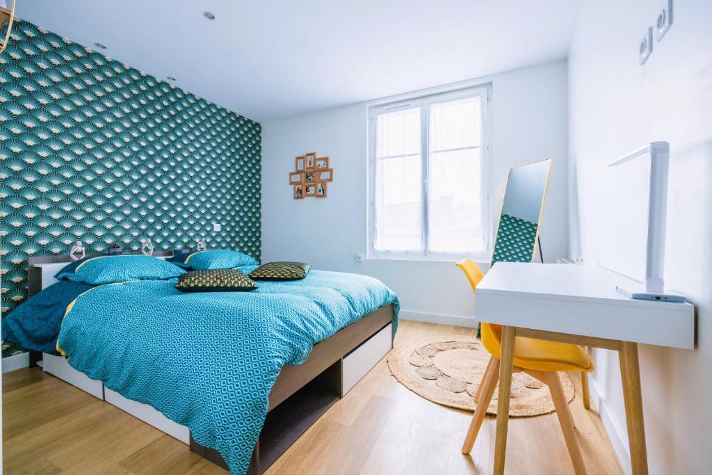 ein blaues Schlafzimmer mit einem Bett und einem Schreibtisch in der Unterkunft Appartement de standing - coeur de Rezé / 10min de Nantes in Rezé