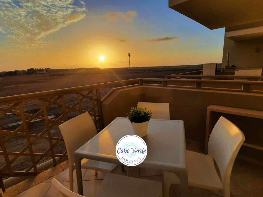 a table and chairs on a balcony with the sunset at Sunset house Cabo Verde in Santa Maria