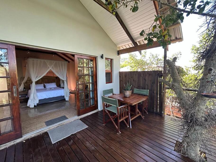 a wooden deck with a bed and a wooden table at Tree Symphony in Marloth Park