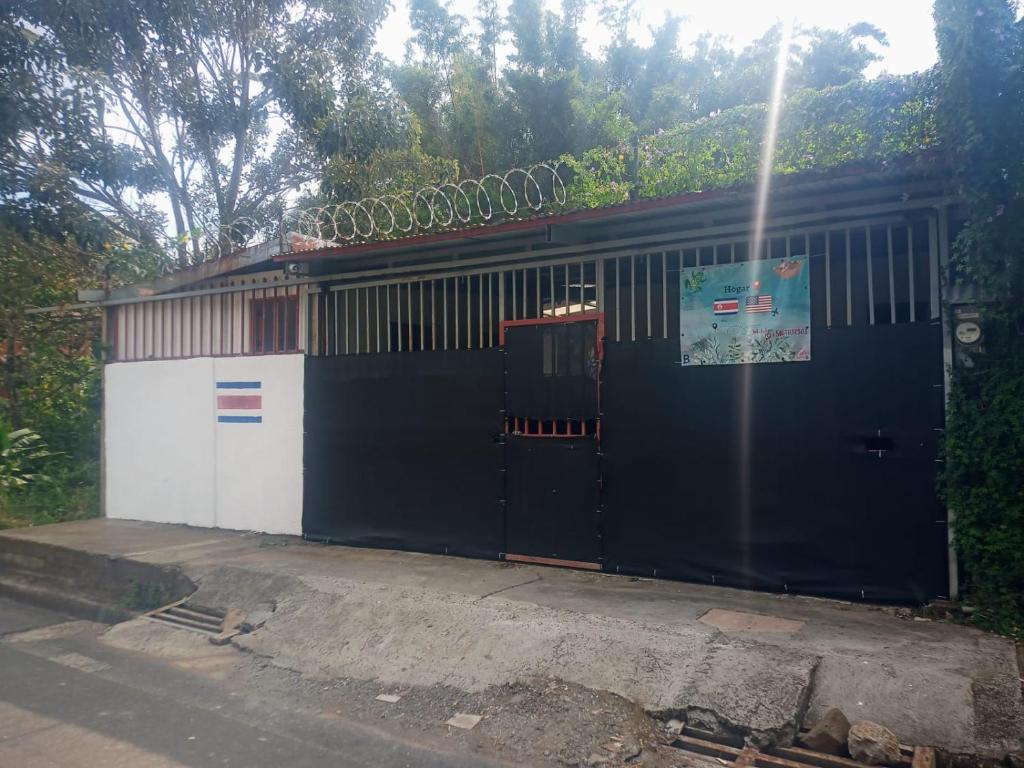 un grand bâtiment noir et blanc avec un portail dans l'établissement Hogar tico-estadounidense cerca de aeropuerto, à Alajuela