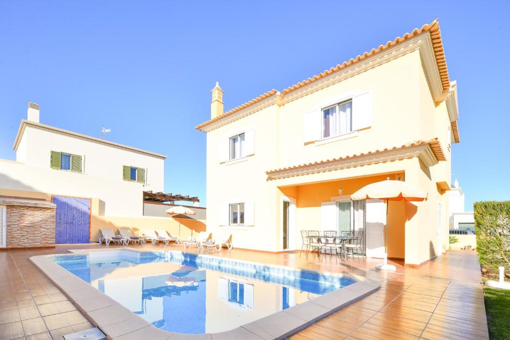 uma villa com piscina em frente a uma casa em Vila com piscina a 5 minutos da Praia em Alcantarilha