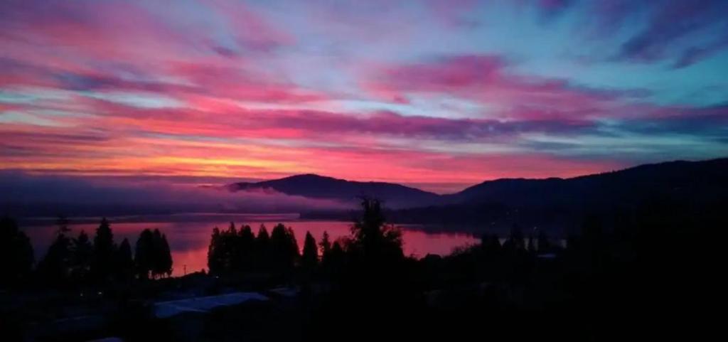 a sunset over a lake with trees and mountains at Spiritview Bellevue in Bellevue