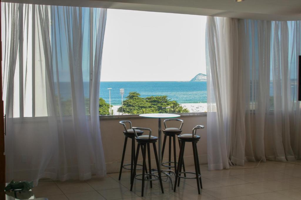 una mesa y sillas en una habitación con vistas al océano en 3 suítes Copacabana vista mar, en Río de Janeiro