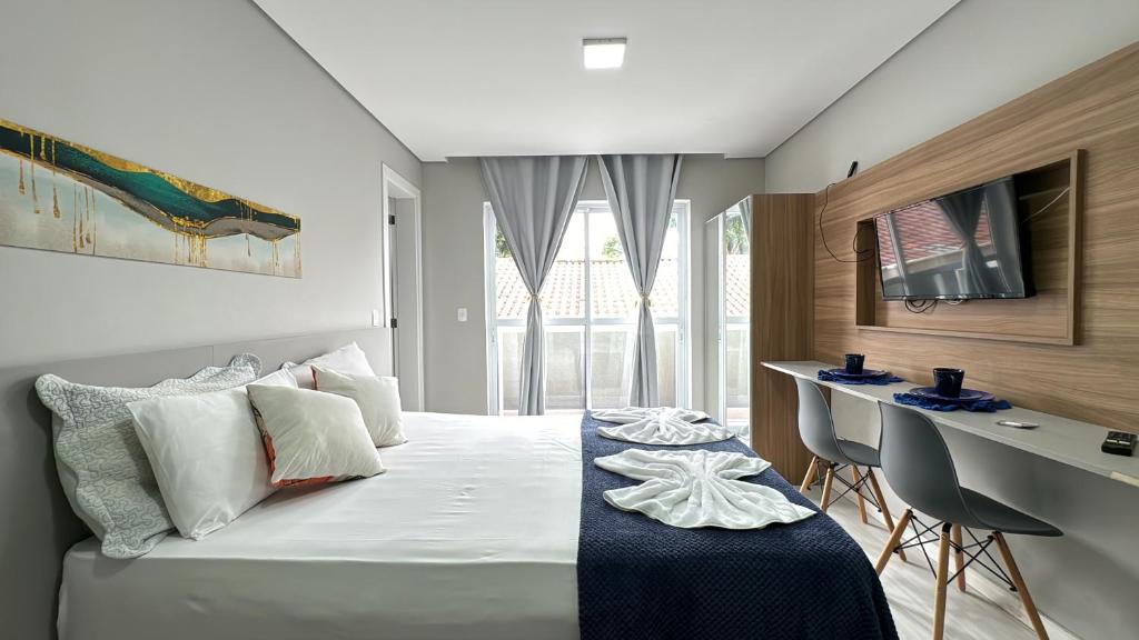 um quarto com uma cama, uma secretária e uma janela em 3-Studio lindamente decorado! Ideal para casal!!! em Curitiba