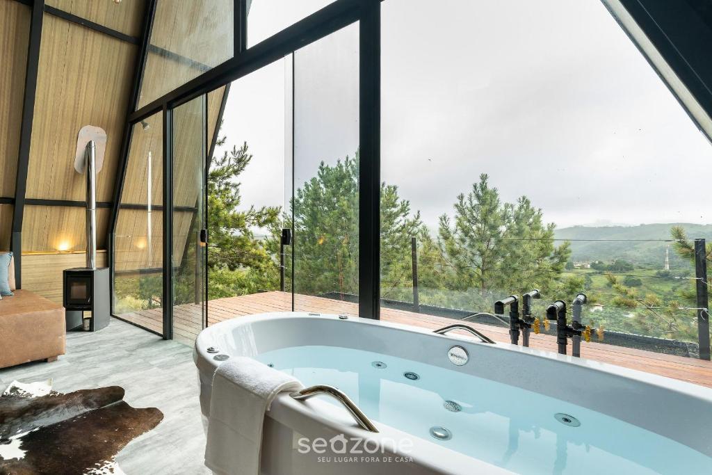 bañera en una habitación con ventanas grandes en Chales Naturale - Campos do Jordão - CNA en Campos do Jordão