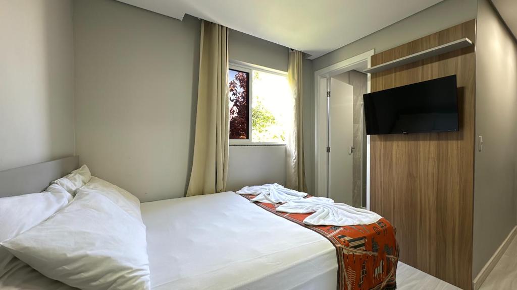 um quarto com uma cama e uma televisão de ecrã plano em 07-STUDIO ENCANTADOR PARA CASAL em Curitiba