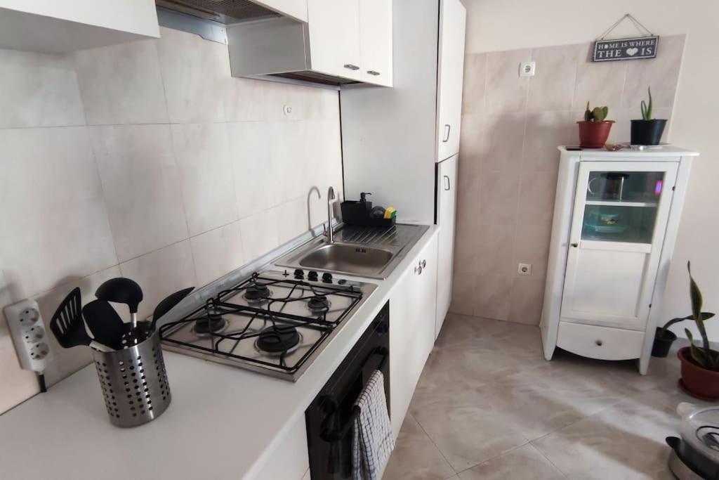a small kitchen with a stove and a sink at Lovely 1 Bedroom flat w/ WiFi and 5 min from beach in Santa Maria