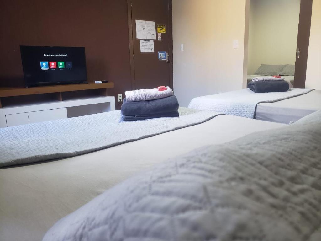 a room with two beds and a flat screen tv at Hospedagem Costa BNU - PLUS in Blumenau