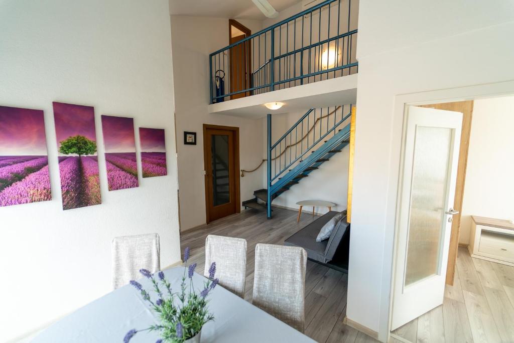 a dining room with a staircase and purple paintings on the wall at Apartment Kodi in Privlaka