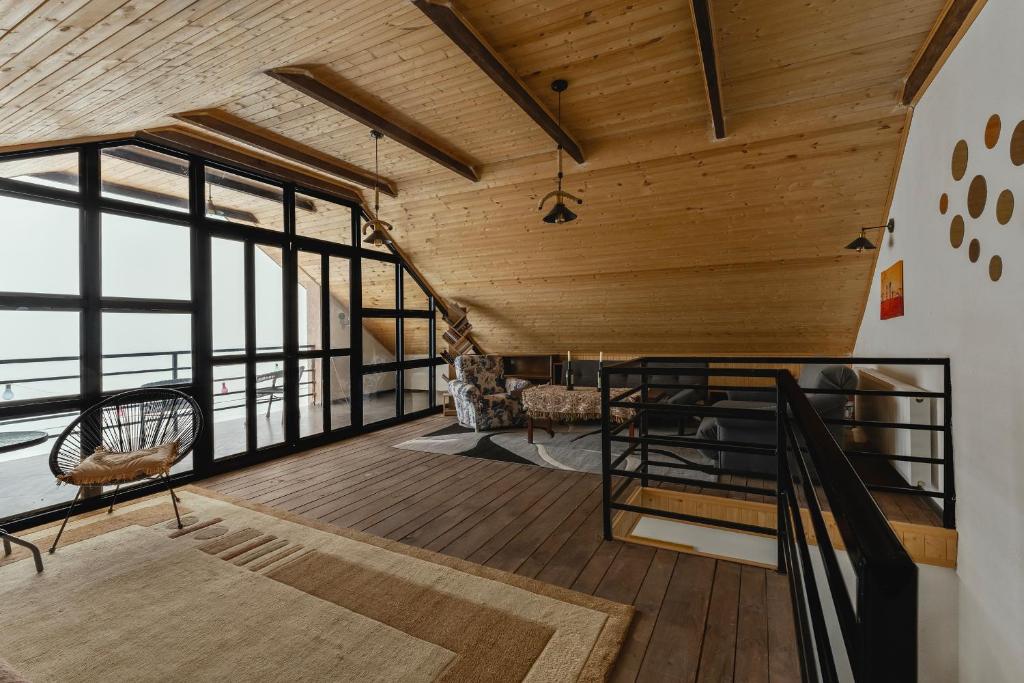 ムツヘタにあるNectar Villa Mukhadtskaro / ვილა ნექტარი მუხადწყაროの木製の天井と窓が備わる広い客室です。