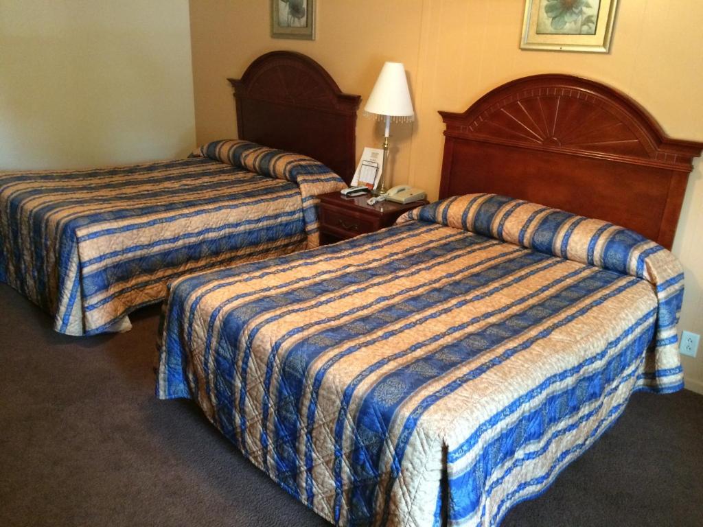 una habitación de hotel con 2 camas y una lámpara en Howards Motel, en Marshall