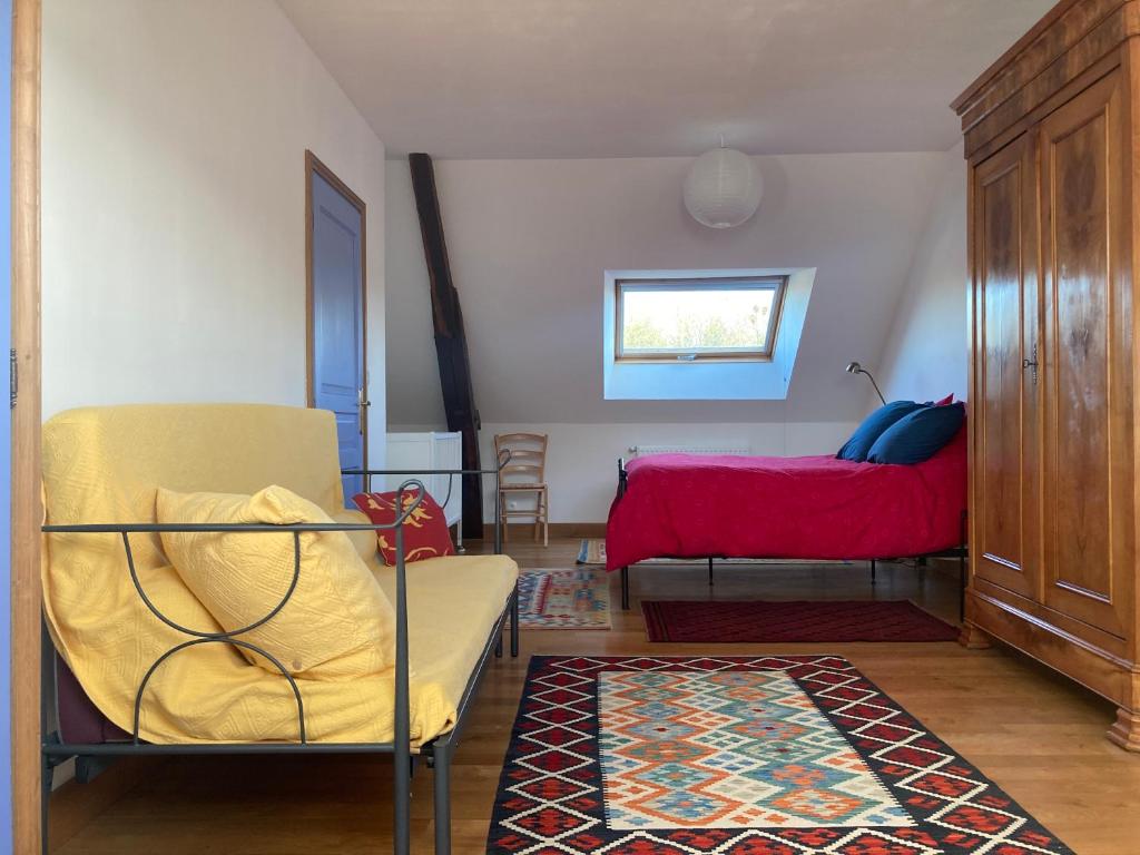 uma sala de estar com uma cadeira e uma cama em Le Poulailler em Loué