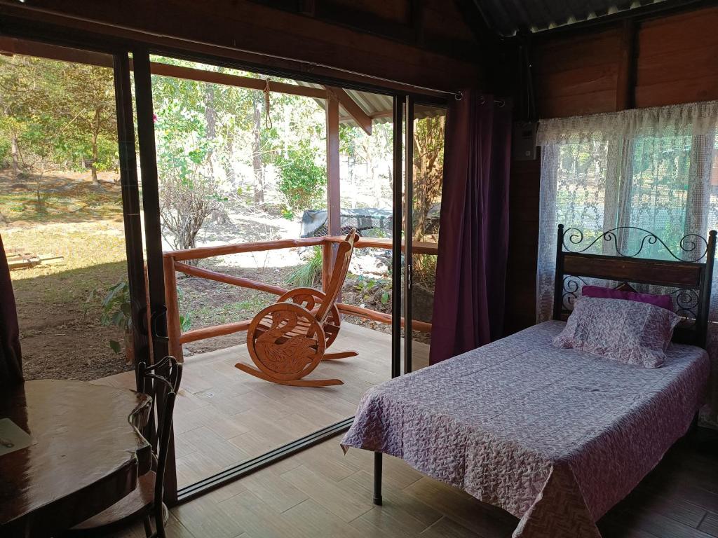 - une chambre avec un lit et une porte coulissante en verre dans l'établissement Cabaña la granja, à Liberia