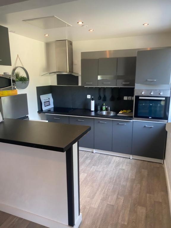 une cuisine avec des armoires bleues et un comptoir noir dans l'établissement Maison lea, à Caen