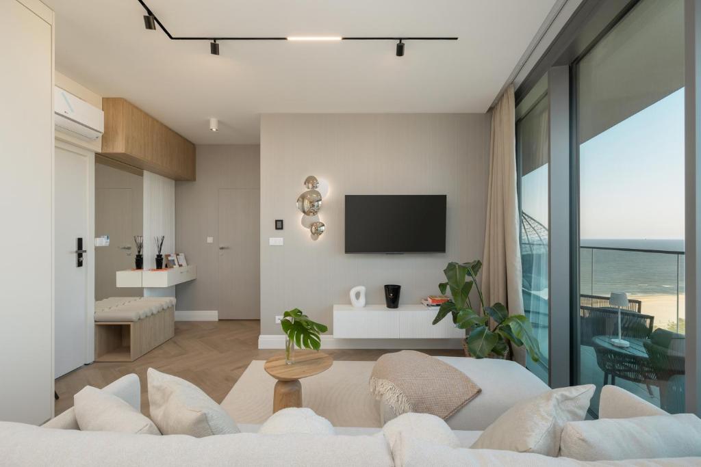 ein Wohnzimmer mit einem weißen Sofa und einem TV in der Unterkunft Wave Międzyzdroje Sea and Molo View MORENORENT in Misdroy