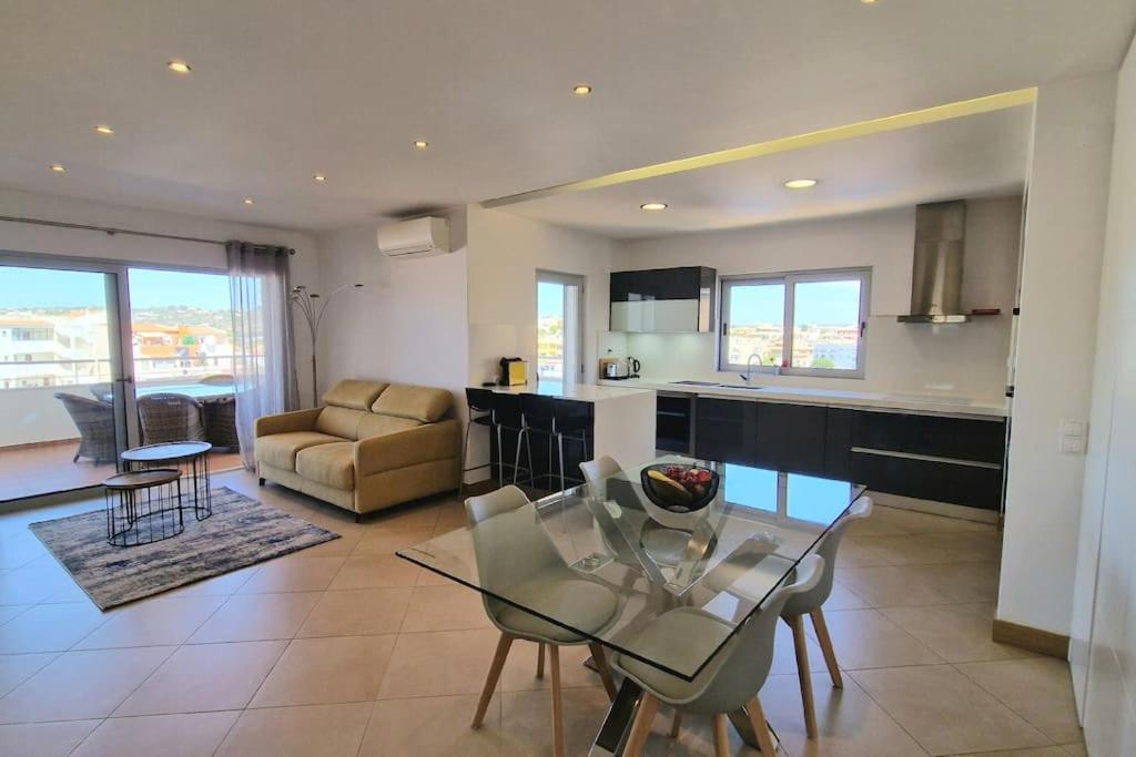 uma cozinha e sala de estar com uma mesa de vidro e cadeiras em Deluxe 2 bedroom apartment with BBQ em Lagos
