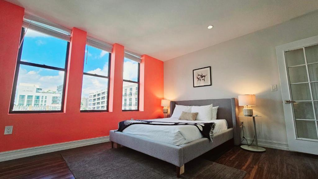 a bedroom with red walls and a bed and windows at The Lofts on Clematis 402 Downtown West Palm Beach in West Palm Beach