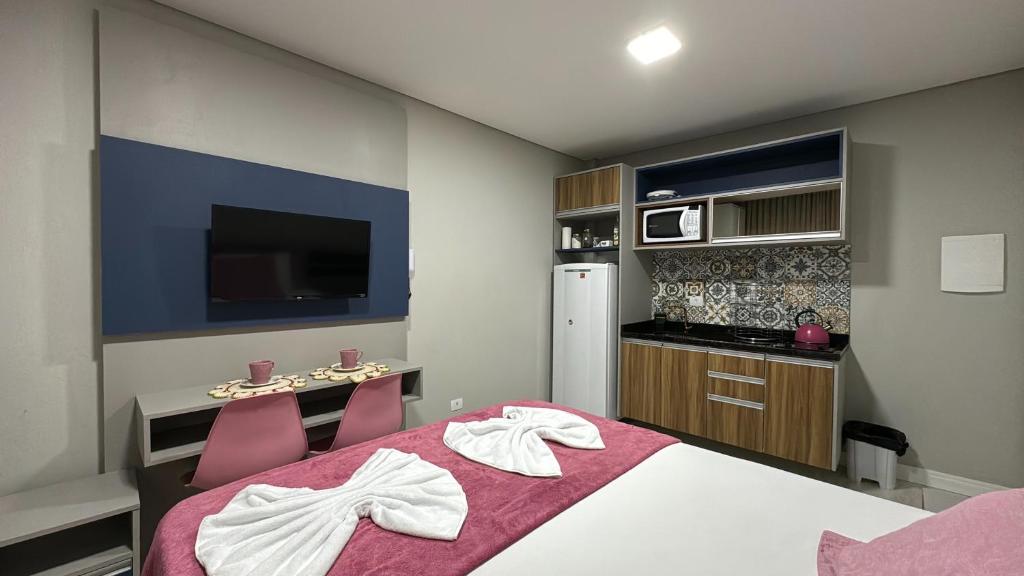 een slaapkamer met een bed, een bureau en een televisie bij 14- Studio decorado com ótima localização!!! in Curitiba