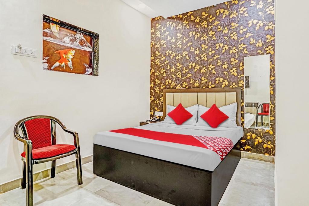 a bedroom with a bed and a red chair at OYO Flagship Hotel Smbha Palace in Mumbai