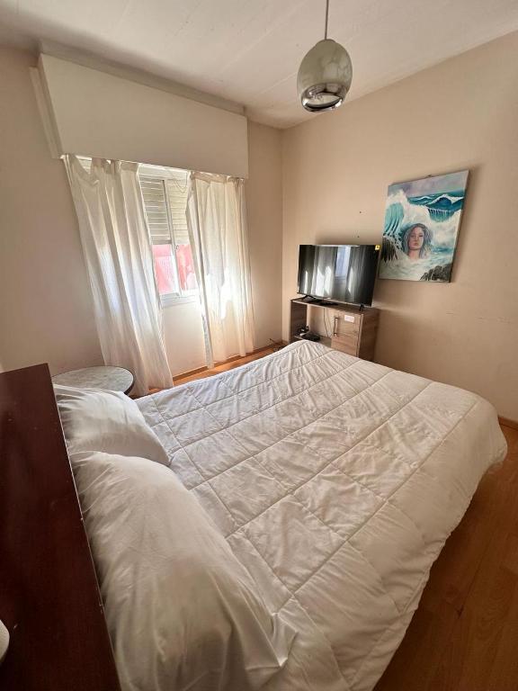 a large white bed in a bedroom with a television at Apart Centro in Comodoro Rivadavia