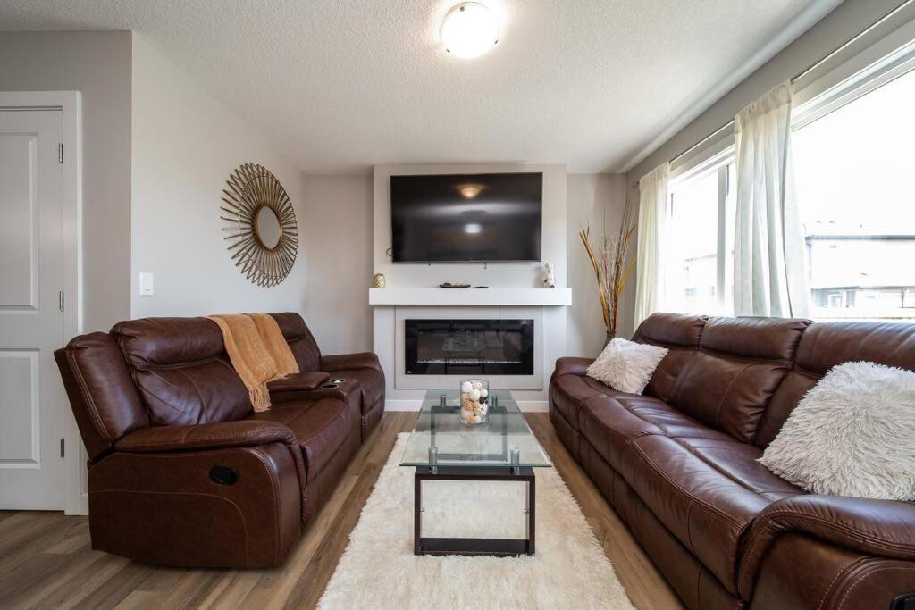 sala de estar con sofá de cuero y chimenea en 3BDRM Home, 5min to WEM/4min to River Cree Casino en Edmonton