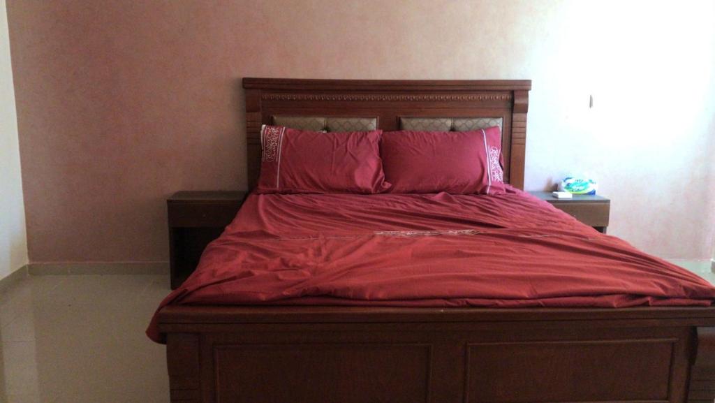 een groot bed met rode lakens en kussens bij شقة لقضاء عطلة مميزة بمدينة الفنيدق in Riffiene