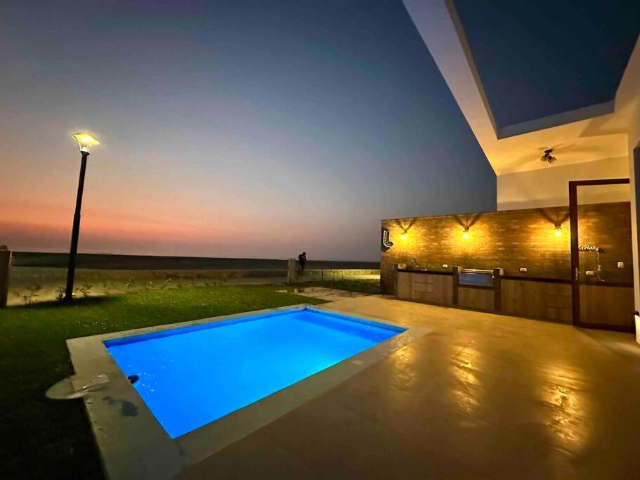 a swimming pool in front of a house at night at Viamar Chincha® Casa de Playa con Piscina 1er fila in Sunampe