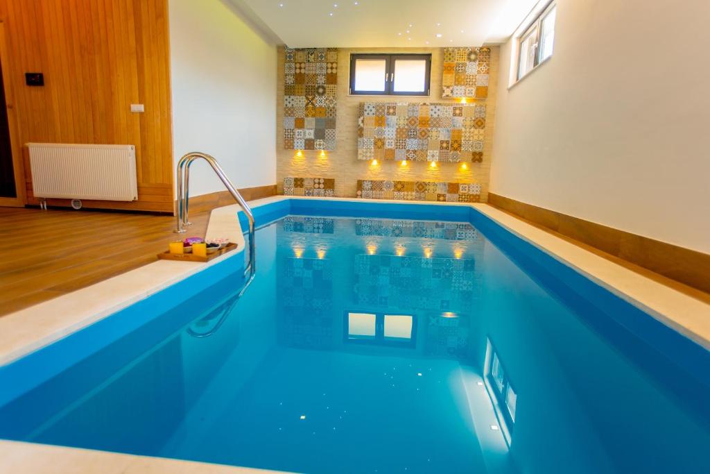 a large swimming pool with blue water in a room at Villa Rose in Sarajevo
