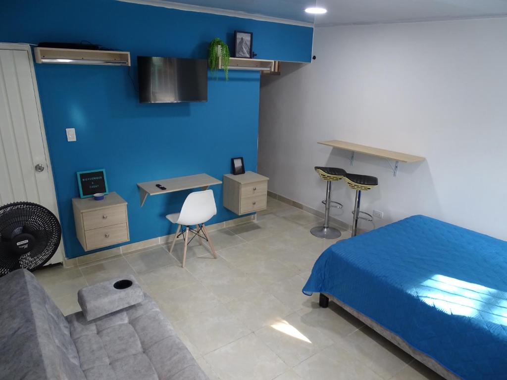 Apartamento en el sur de Cali في كالي: غرفة نوم بجدران زرقاء وسرير ومكتب