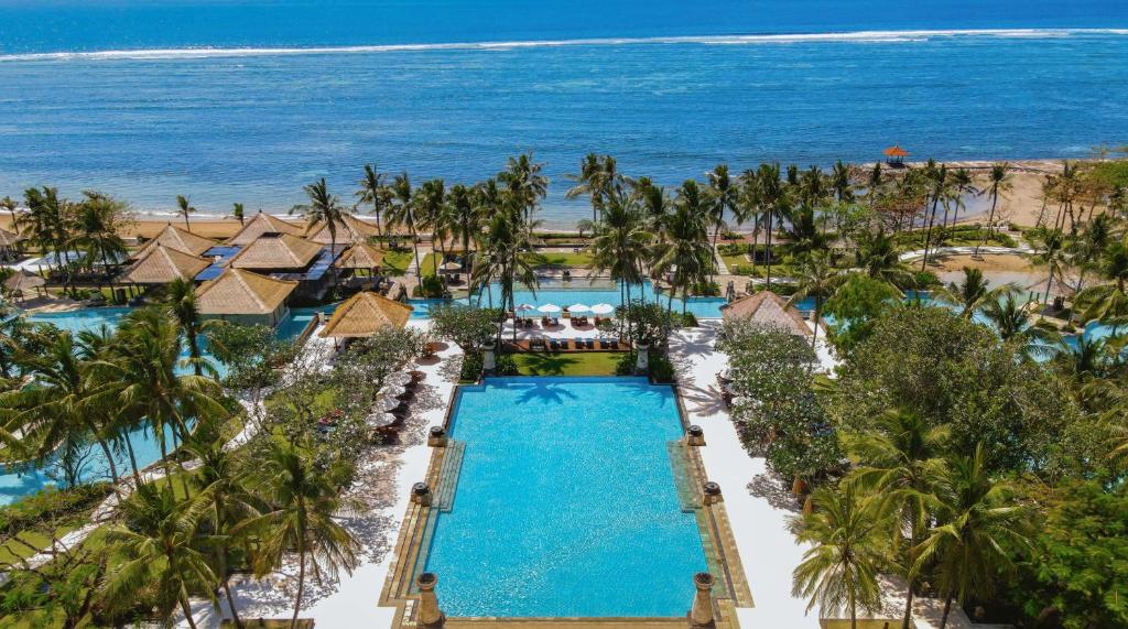 an aerial view of a resort with a pool and the ocean at Conrad Bali in Nusa Dua