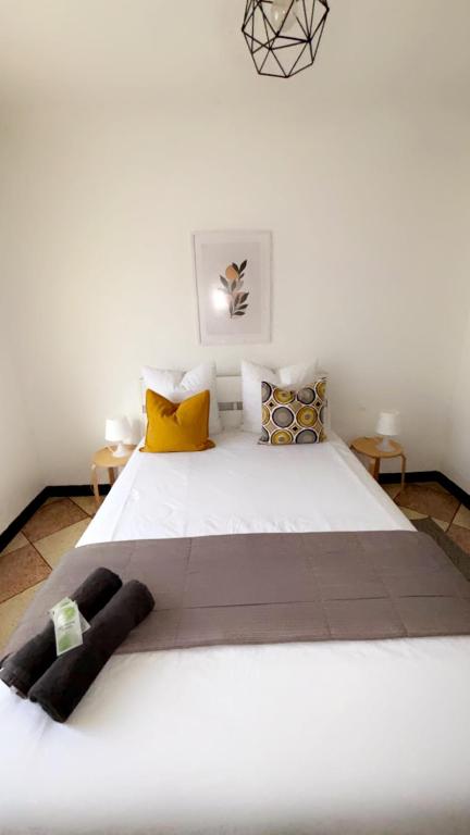 - une chambre avec un grand lit blanc et des oreillers jaunes dans l'établissement appartement L'OLIVIER, à Arles